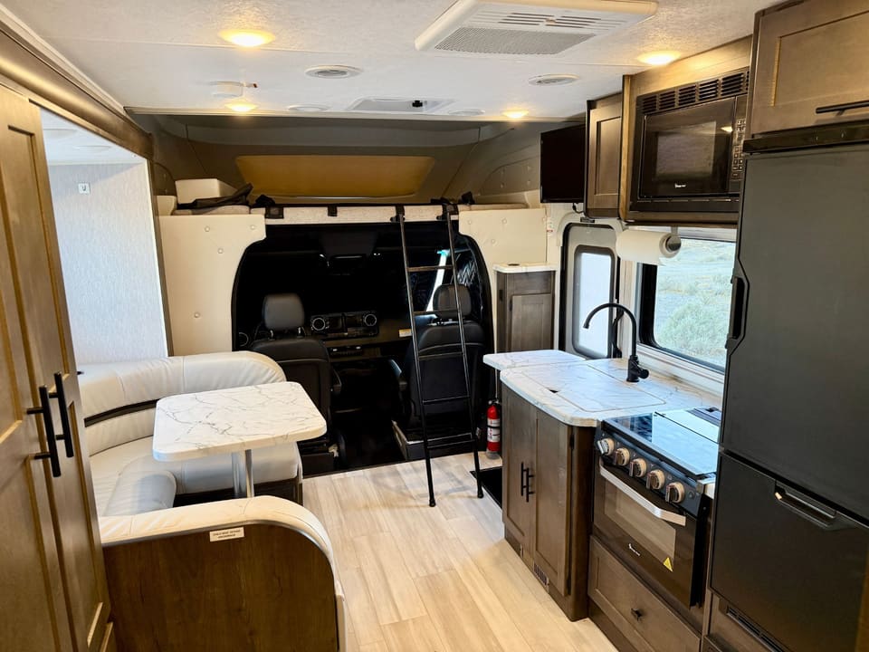 View toward the cab showing the cab-over bunk with ladder, dinette and kitchen